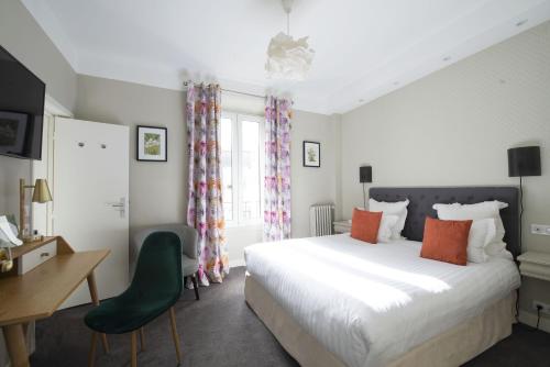a bedroom with a bed and a desk and a chair at Hôtel des Batignolles in Paris