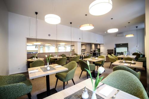 a dining room with tables and green chairs at City Partner Hotel Berliner Hof in Karlsruhe