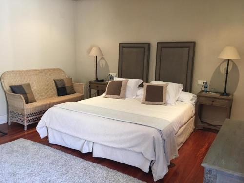 a bedroom with a large white bed and a chair at Narbasu Restaurante y Hotel in Cereceda