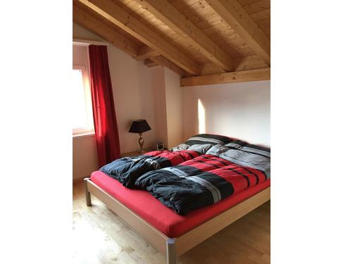 Bett mit einer roten und schwarzen Bettdecke in einem Zimmer in der Unterkunft Ferienwohnung Vazerol in Brienz