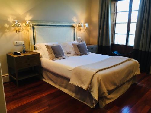 a bedroom with a large bed with white sheets and pillows at Narbasu Restaurante y Hotel in Cereceda