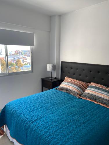 1 dormitorio con cama azul y ventana en Mandala - El Palomar en El Palomar