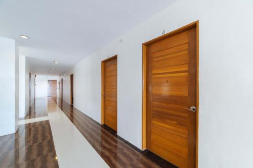 a hallway with wooden doors and white walls at RedDoorz Plus @ San Roque Roxas City in Roxas City