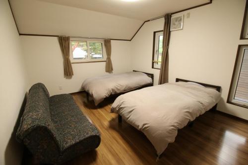 a bedroom with two beds and a bench in it at Cottage All Resort Service / Vacation STAY 8444 in Inawashiro