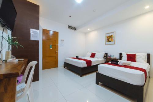 a hotel room with two beds and a desk at RedDoorz Plus @ San Roque Roxas City in Roxas City