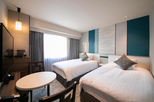 a hotel room with two beds and a table at Hotel JAL City Nagasaki in Nagasaki