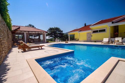 a swimming pool with a bench next to a house at Villa Delmati in Tugare