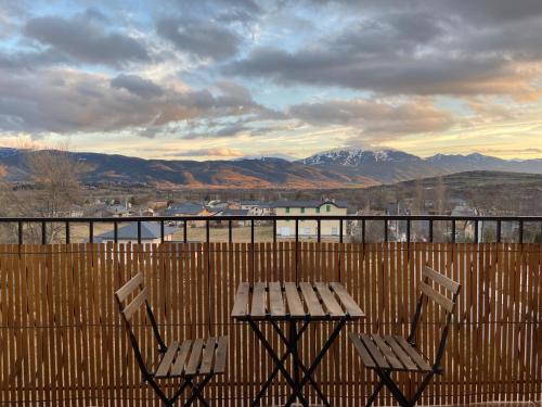a picnic table and chairs on a balcony with mountains at Les Cyprès in Enveitg