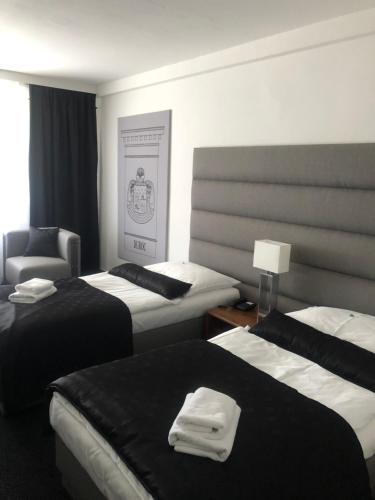 a hotel room with three beds and a chair at A-Austerlitz Hotel in Brno