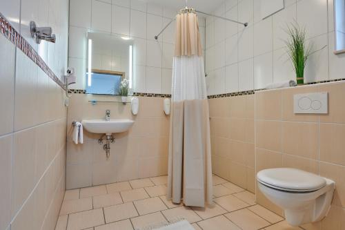 ein Bad mit einem WC, einem Waschbecken und einer Dusche in der Unterkunft Sunny Hotel Straubing in Straubing