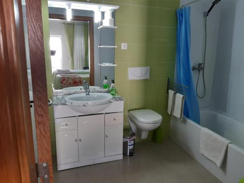 een badkamer met een wastafel, een toilet en een spiegel bij Alojamento Rita in Mértola