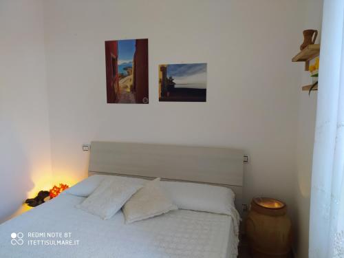 a bedroom with a white bed with two pictures on the wall at I Tetti Sul Mare in Tellaro