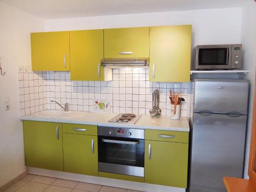 La cuisine est équipée de placards jaunes et d'un réfrigérateur en acier inoxydable. dans l'établissement Holiday Home Les Capellanes-3 by Interhome, à Saint Cyprien Plage