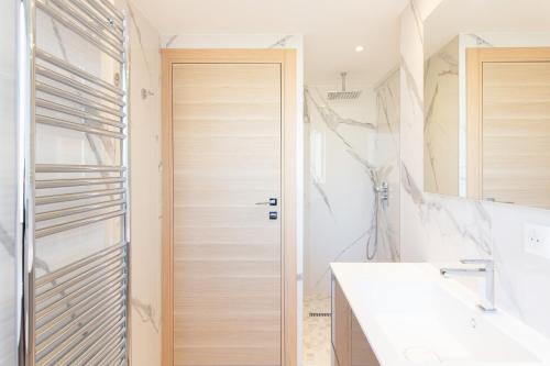 La salle de bains est pourvue d'une porte en bois et d'un lavabo. dans l'établissement On La Croisette: new 2 bedrooms with sea view, à Cannes