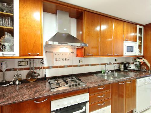 a kitchen with wooden cabinets and a stove top oven at Apartment Edificio Blanqueries-2 by Interhome in Calella