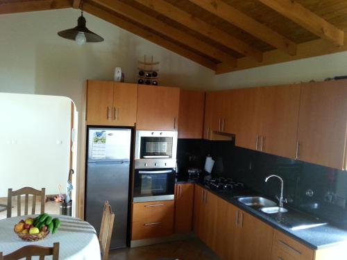 Una cocina con gabinetes de madera y un refrigerador y una mesa. en Casa da Caixeira, en Arco da Calheta