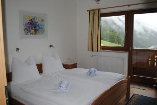 a bedroom with a white bed with blue slippers on it at Landhaus Stöckl in Finkenberg