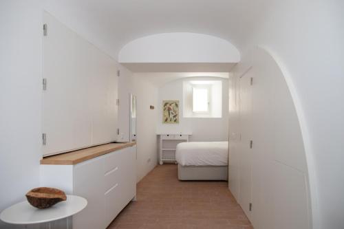 a white bedroom with a bed and a table at Casa da Travessa in Évora