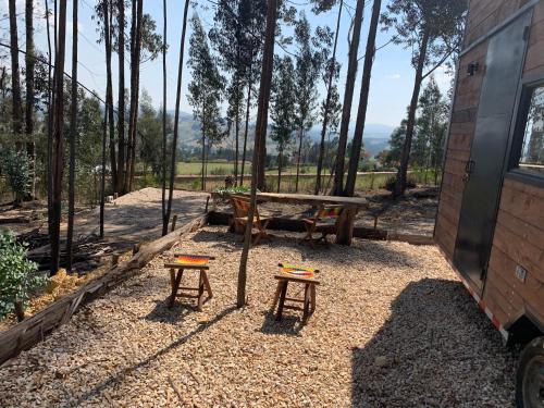 a picnic table and two stools next to a trailer at El Bosque de Paipa in Paipa