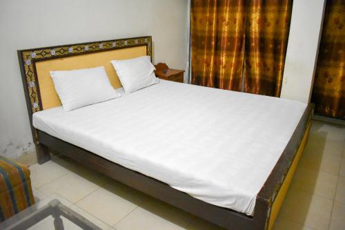 ラホールにあるAl Haider Hotelのベッドルーム(白いシーツを使用した大型ベッド1台付)