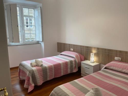 a bedroom with two beds and a window at Pensión Hedrass in Santiago de Compostela