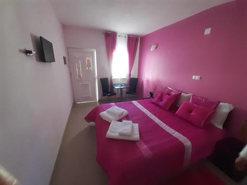 Dormitorio rosa con cama grande con almohadas rosas en Alojamento Rita en Mértola