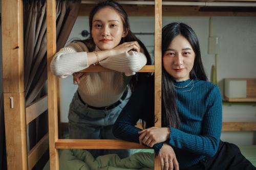 two women are sitting on a bunk bed at T-Life Hostel in Longjing