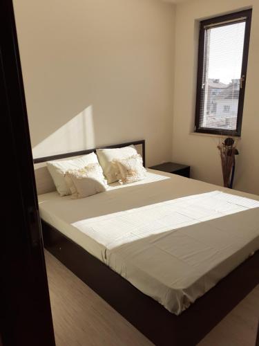 1 dormitorio con 1 cama con sábanas blancas y ventana en Apartament Emi, en Sandanski