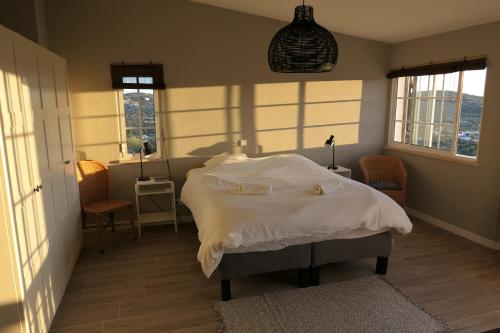1 dormitorio con 1 cama con sábanas blancas y ventanas en Villa De Hofnar, en Soalheira