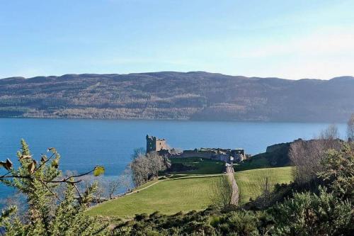 a castle on a hill next to a body of water at Herons Rest in Drumnadrochit