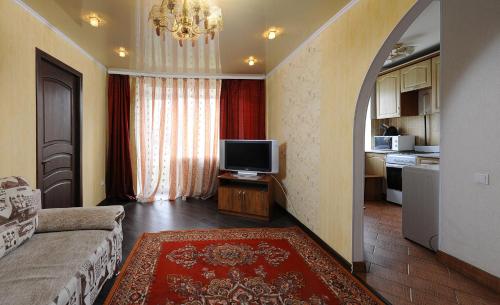 オムスクにあるOmsk Sutki Apartments on Sportivnyi proezd 12のリビングルーム(ソファ、テレビ付)、キッチン