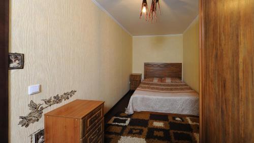 オムスクにあるOmsk Sutki Apartments on Sportivnyi proezd 12の小さなベッドルーム(ベッド1台、木製ドレッサー付)