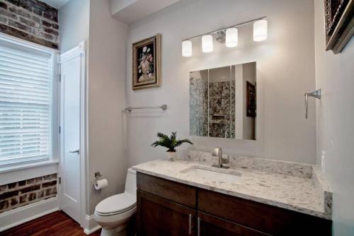 a bathroom with a sink and a toilet and a mirror at Sophisticated Historic Remodeled 9 bedroom Home in Savannah