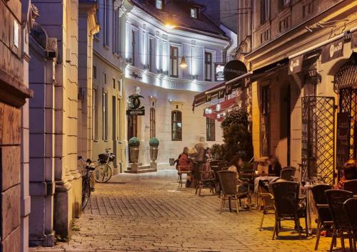 a street with people sitting at tables in an alley at Boutique Hotel Chrysso in Košice