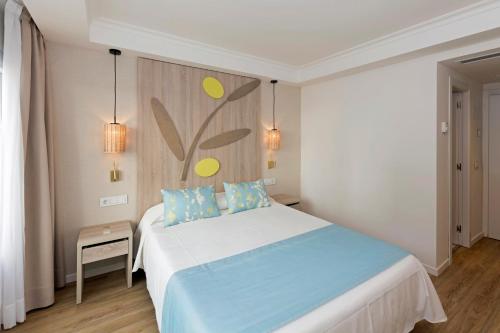 a bedroom with a bed with blue and green pillows at HSM Solivera in Paguera