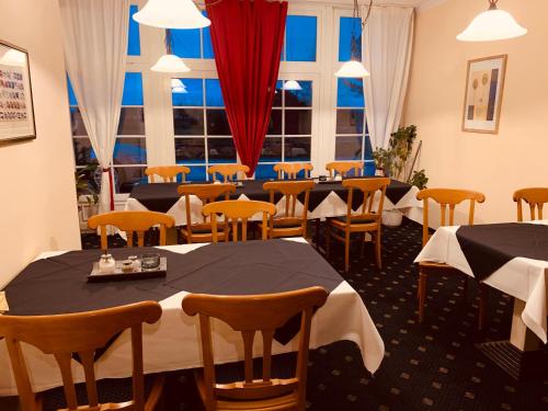 a restaurant with tables and chairs and a window at Hotel Zum Strand in Warnemünde
