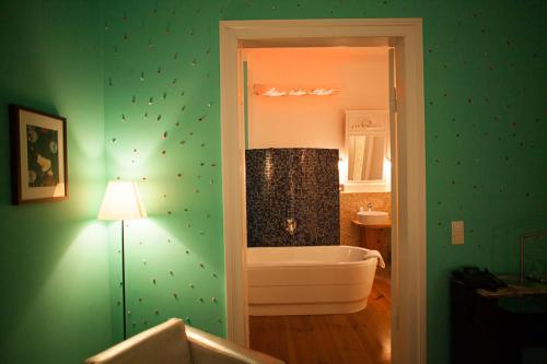 a bathroom with a tub and a green wall at Arte Luise Kunsthotel in Berlin