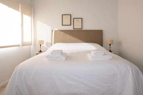 Una cama blanca con dos toallas encima. en San Martin Garden en San Martín de los Andes