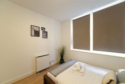 - une chambre avec un lit et une grande fenêtre dans l'établissement Bright Central London Apartments by DC London Rooms, à Londres