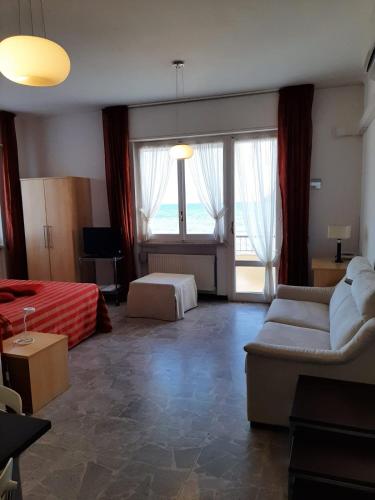 a living room with a couch and a bed and windows at Residence Sole in Albenga