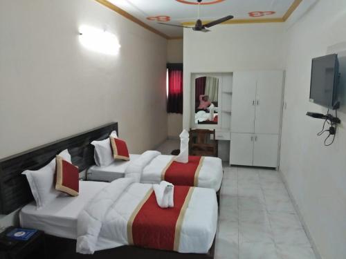 um quarto de hotel com três camas e uma televisão em HOTEL BUDDHA em Kushinagar