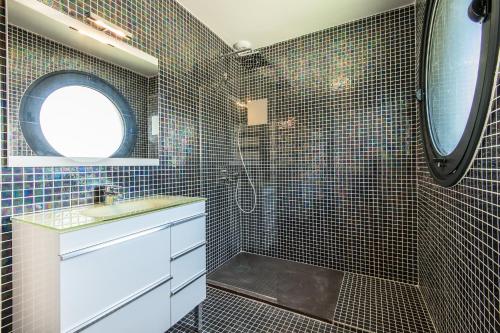 een badkamer met een douche, een wastafel en een spiegel bij Les Cottages d'ANADARA in Anglet