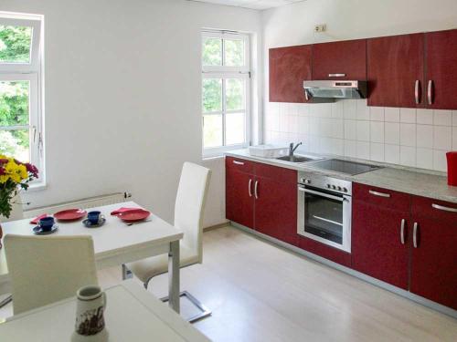 a kitchen with red cabinets and a white table with a table sidx sidx at Ferienwohnung Bernhardt in Zella-Mehlis