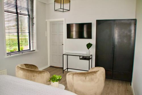um quarto com uma cama, 2 cadeiras e uma secretária em De Heerlijkheid van Noordwelle Adults Only em Noordwelle