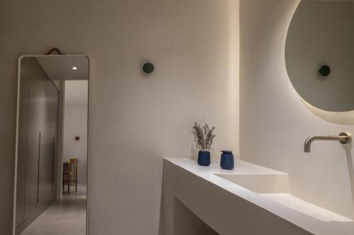 a white bathroom with a sink and a mirror at The Saint Hotel in Oia