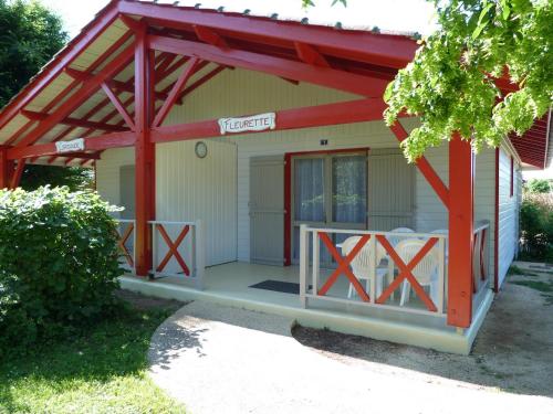 a smallshed with a red metal roof and a porch at Gites de la Garenne in Nérac