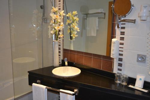 a white sink sitting under a mirror in a bathroom at SPA Sercotel Odeón in Ferrol