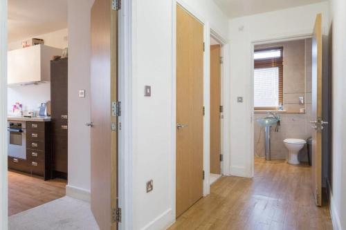 a kitchen with white walls and wooden floors and a bathroom at City view apartment in Birmingham