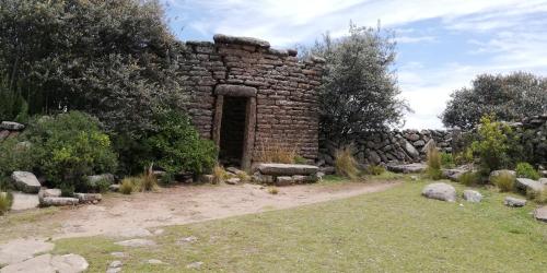 an old brick building with a doorway in a garden at Taquile Hospedaje Mario in Huillanopampa