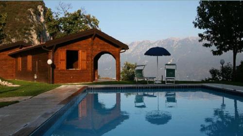 a swimming pool in front of a house with an umbrella at Residence Hotel Montegargnano in Gargnano